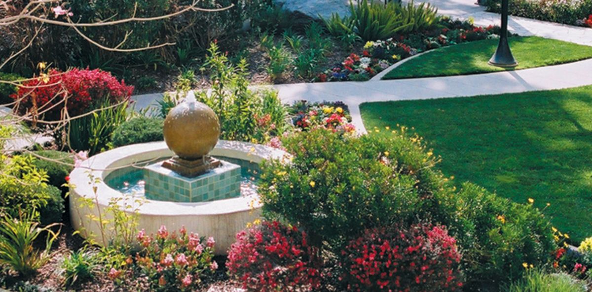 Senior living community, Villa Gardens, showcasing lush gardens, water fountain, and park-like setting.