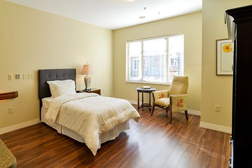 Interior view of a bedroom at Memory Care of Little Rock at Good Shepherd with hardwood flooring.