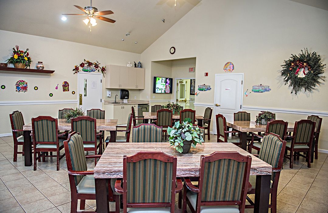 Senior living community dining room with elegant furniture, flower arrangements, and modern appliances.