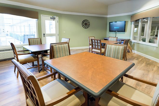 Senior living community interior at Brookdale Kettleman Lane with dining area, TV, and pet dog.