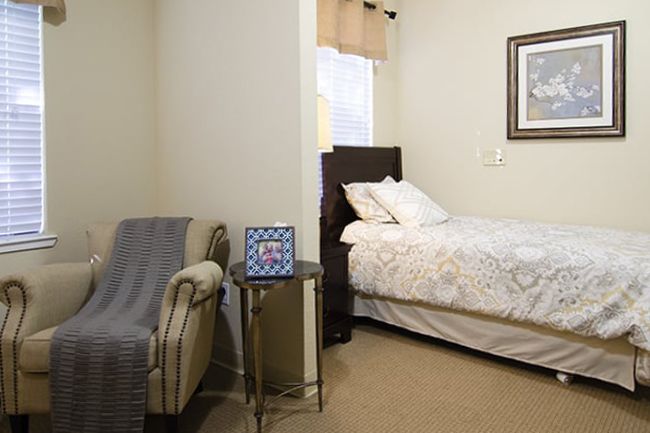 Senior living community bedroom at Sterling Court At Roseville with cozy furniture and decor.