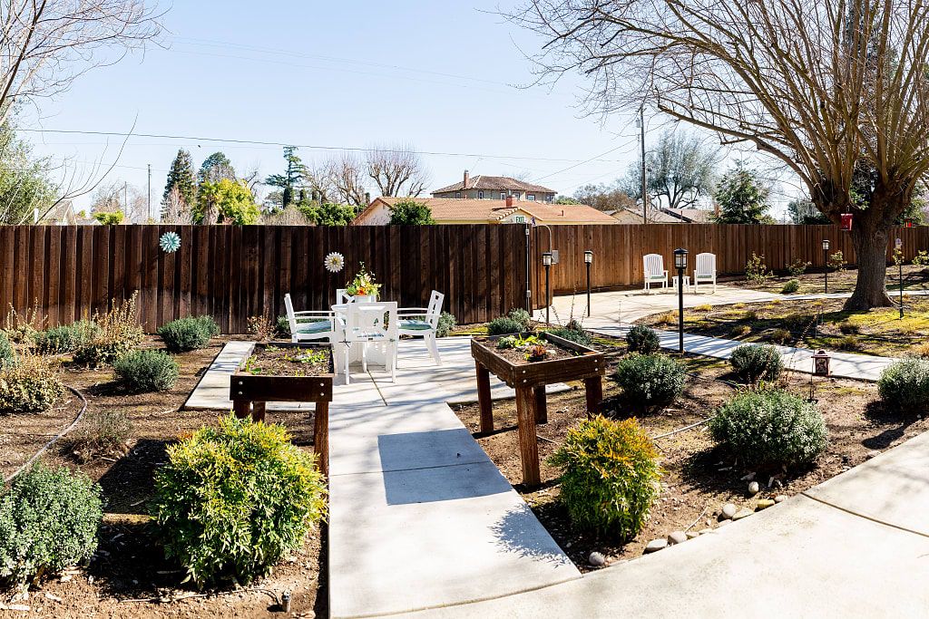 Backyard garden with lush plants and wooden furniture at Astoria Senior Living, Oakdale.