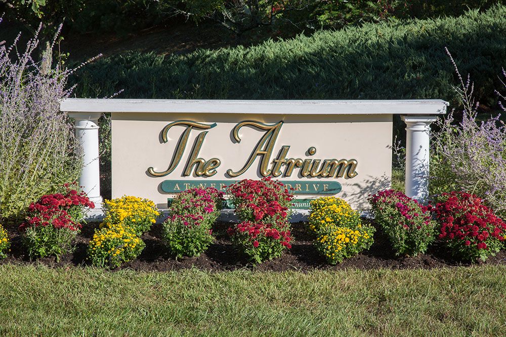 Senior living community, The Atrium at Veronica Drive, featuring a lush garden, park, and lawn.