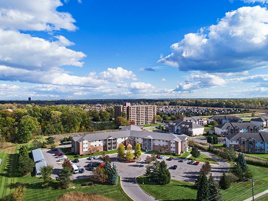 Aerial view of American House Southgate senior living community with lush greenery and cars.