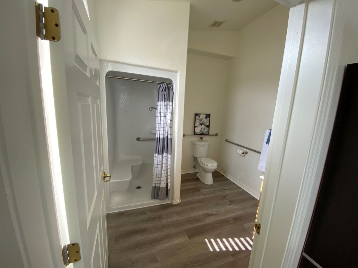 Bathroom with low profile shower, grab bars, built in bench, and adjustable shower head.