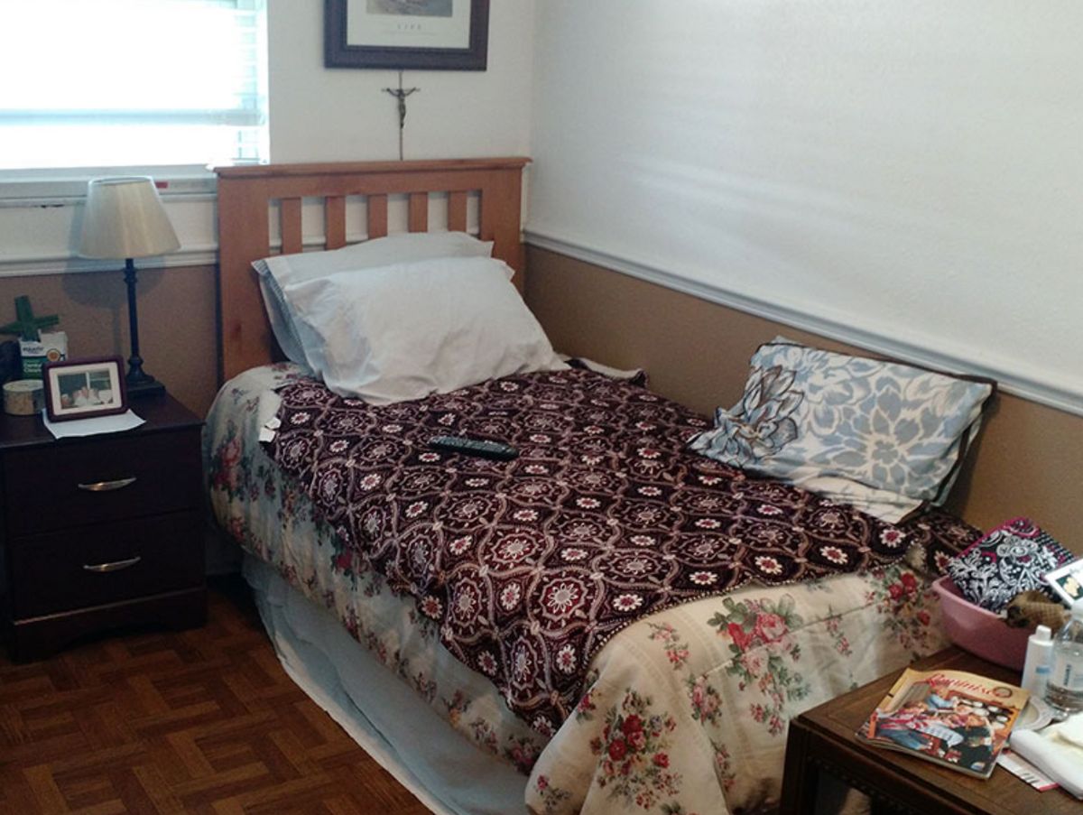 Bedroom setup with furniture, cushion, home decor, and table lamp in Angels Senior Living at North Tampa.