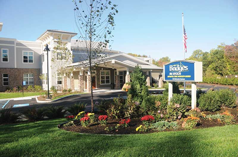 Architectural view of Bridges® By Epoch At Norwalk senior living community with lush lawn.