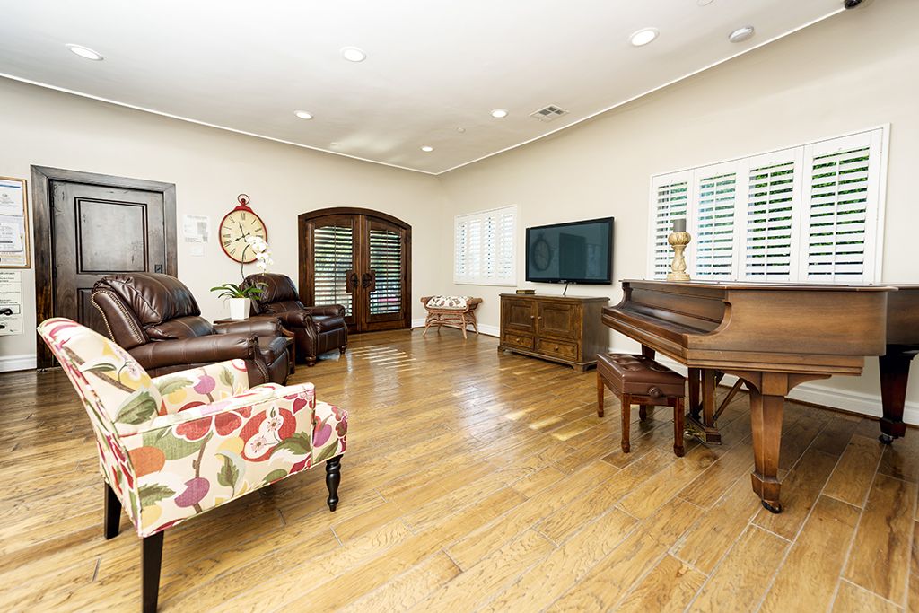 Interior view of Raya's Paradise senior living room with piano, TV, and fireplace.