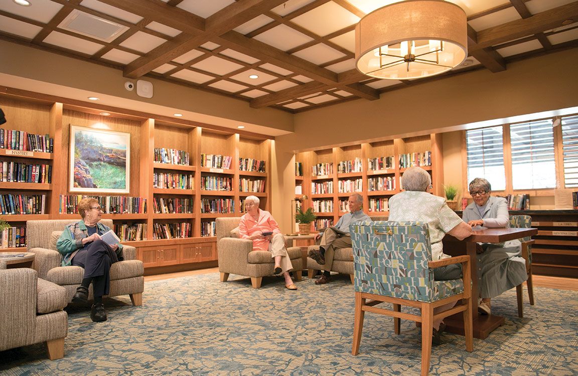 Senior residents and child reading in the library of Villa Gardens community.