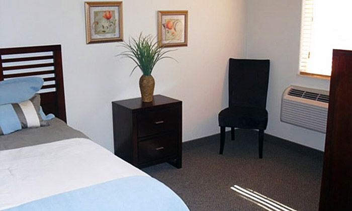 Bedroom interior at Serenity Place Residential Care with bed, chair, decor, and appliances.