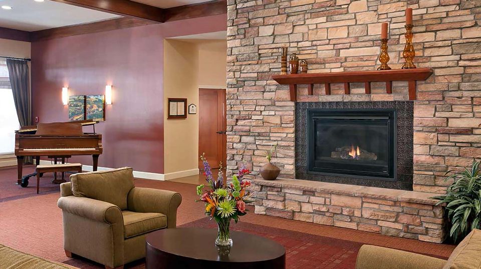 Interior view of Atria Valley View senior living room with piano, fireplace and home decor.