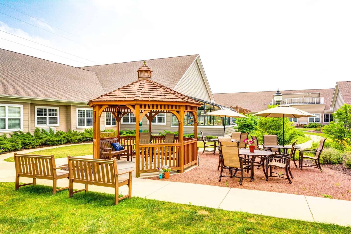 Outdoor and indoor view of The Auberge At Naperville senior living community with lush greenery.