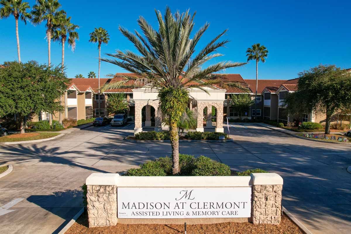 Madison at Clermont senior living community with villas, lush vegetation, and cars.