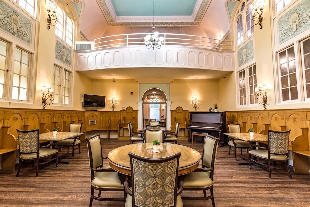 Interior view of St. Andrews Memory Care, featuring dining area, piano, and lounge with modern decor.
