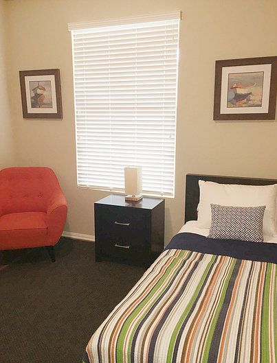 Senior living community bedroom at Accuro Homes II featuring cozy furniture and home decor.