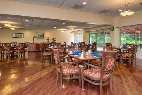 Interior view of Wesley Enhanced Living at Stapeley featuring dining room with wooden furniture and art.