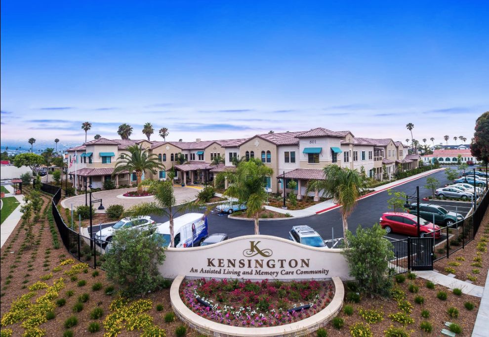 Senior living community, The Kensington Redondo Beach, with lush plants and urban architecture.