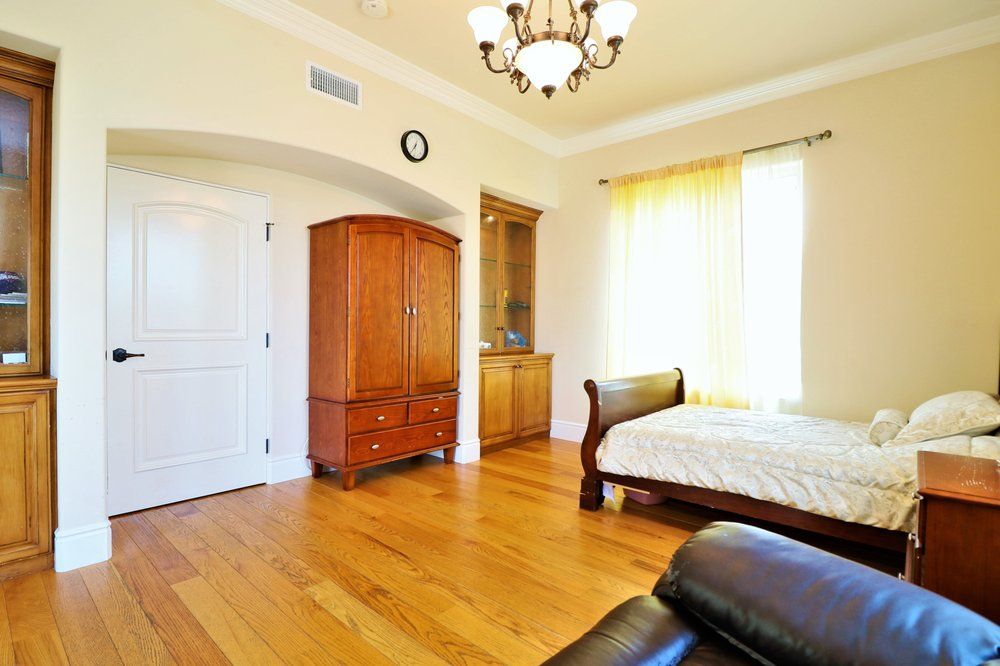 Interior view of a bedroom in Astoria Retirement Residences featuring hardwood flooring and elegant decor.