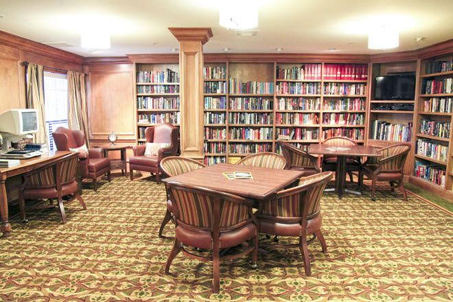 Senior residents enjoying a library with books, computers, and dining furniture at Brookdale Diablo Lodge.