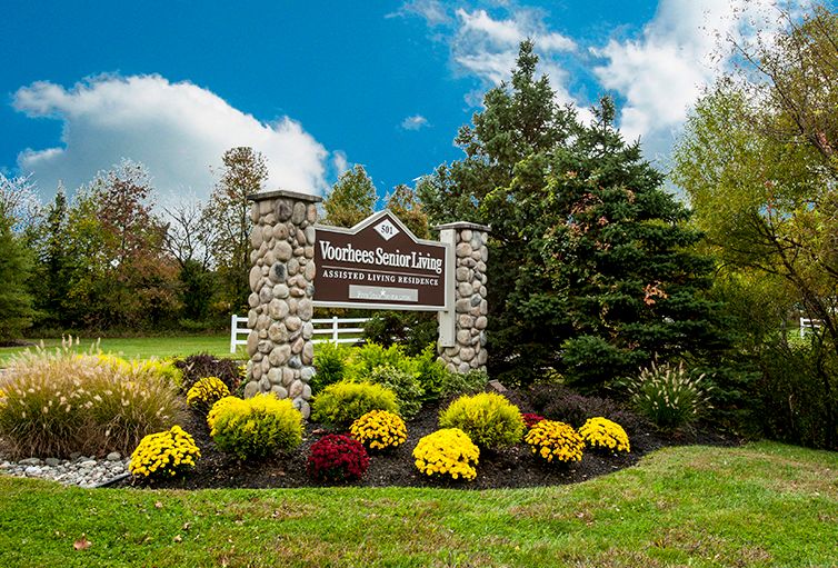 Grassy landscape of Voorhees Senior Living community with trees, flowers, and park area.