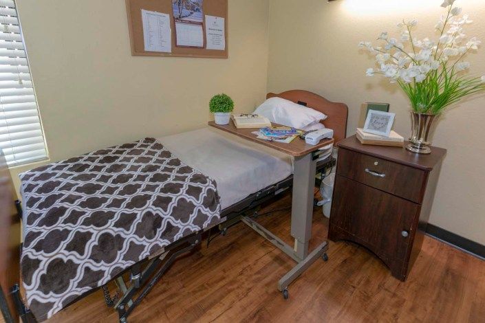 Bed, furniture, and art in a room at Citadel Post Acute senior living community with spa and plants.