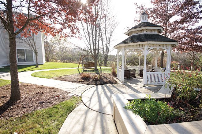 Senior living community Brookdale Ann Arbor featuring a lush backyard with park benches and gazebo.
