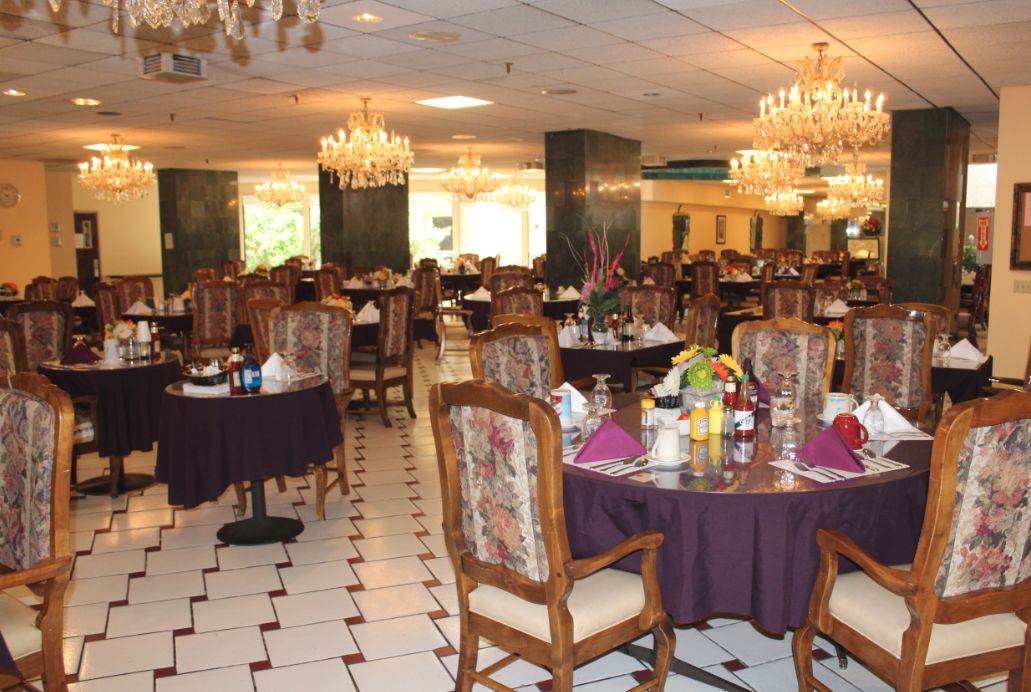 Interior view of Arcadia Gardens Retirement Hotel featuring dining area, reception room, and art decor.