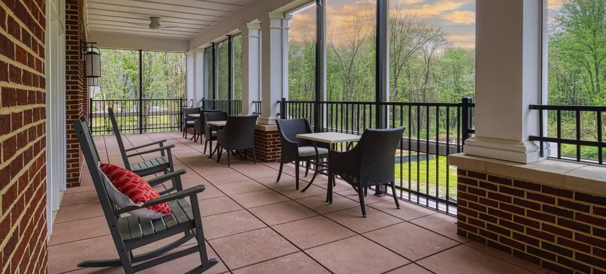 Senior living community Cadence At Olney featuring indoor furniture, outdoor balcony, and scenic nature.