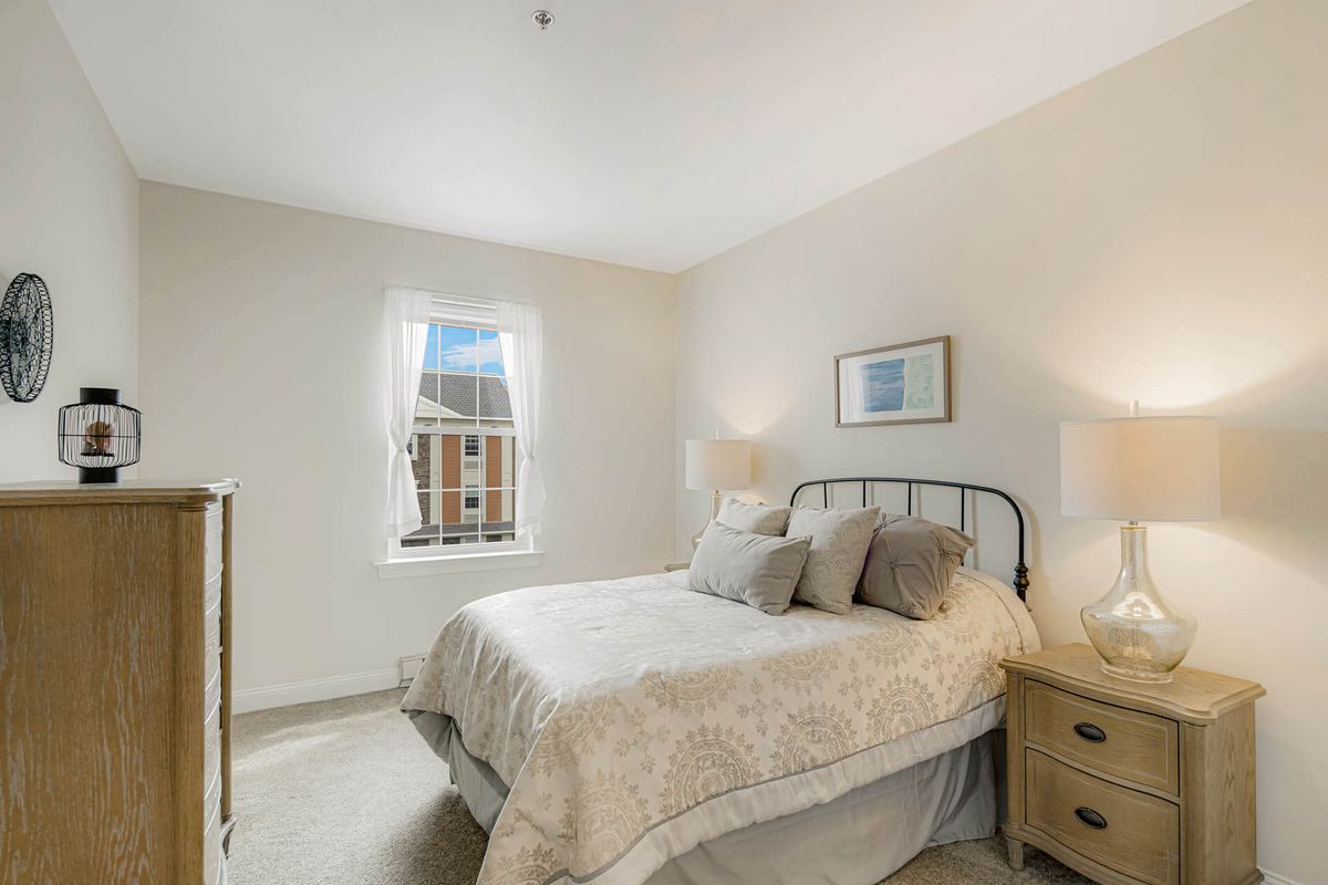 Corner view of a cozy bedroom in Woodbury Mews senior living community, featuring elegant interior design.