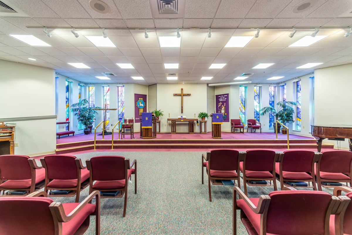 Senior living community chapel with piano, altar, chairs, and plants at Gambrill Gardens.