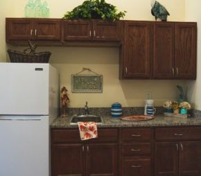 Senior resident in the modern kitchen of Angels Senior Living At Sarasota with appliances.
