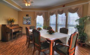Interior view of Charter Senior Living of Gallatin featuring dining area, piano, and home decor.