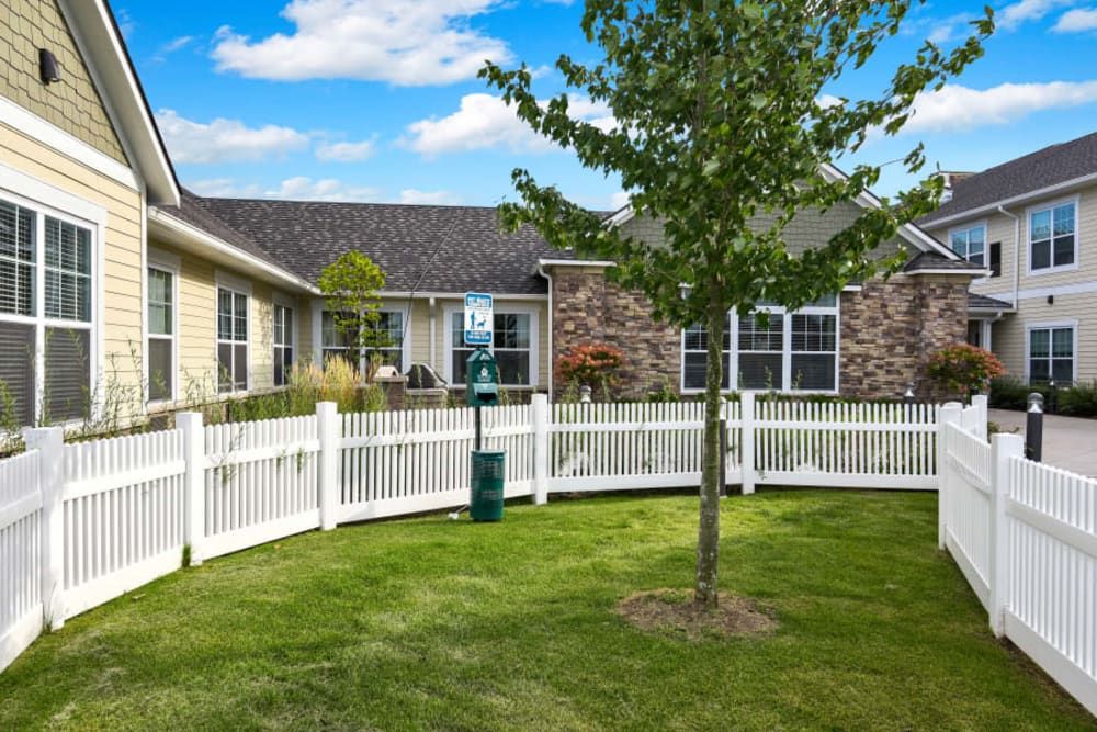 Senior living community, Anthology Of Troy, featuring a lush outdoor yard with a picket fence.