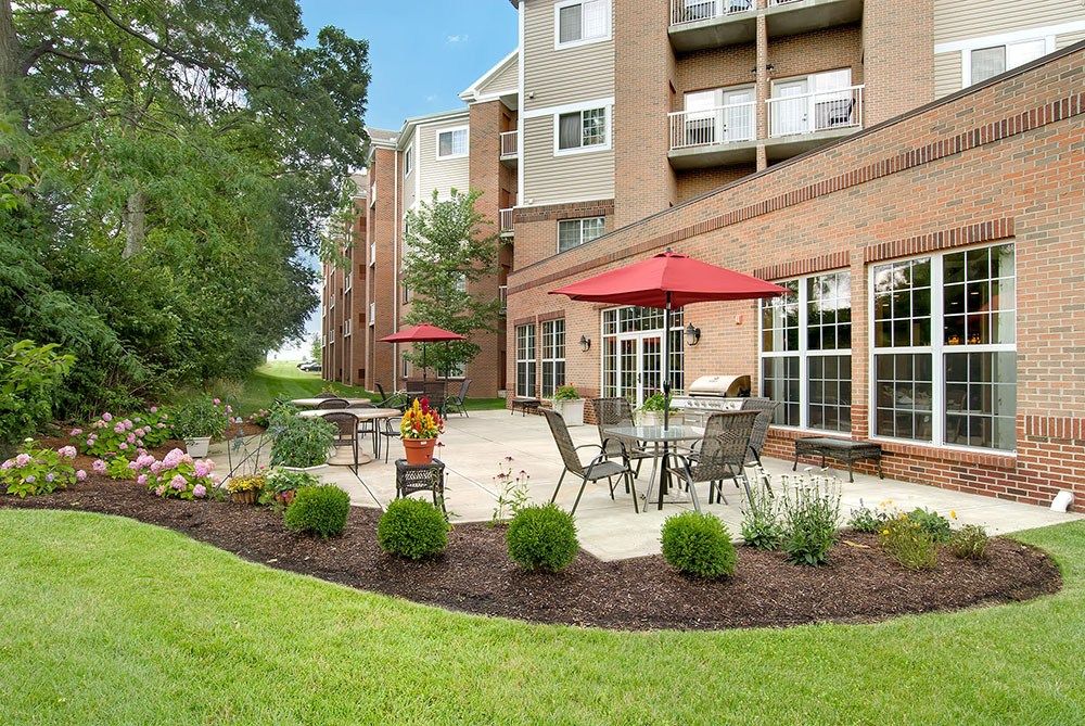 Senior living community, Barrington of West Chester, featuring lush lawns, urban architecture, and patio furniture.