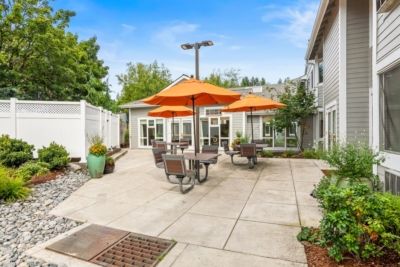 Regency Park Assisted Living and Memory Care facility, featuring outdoor patio, city view, and lush greenery.