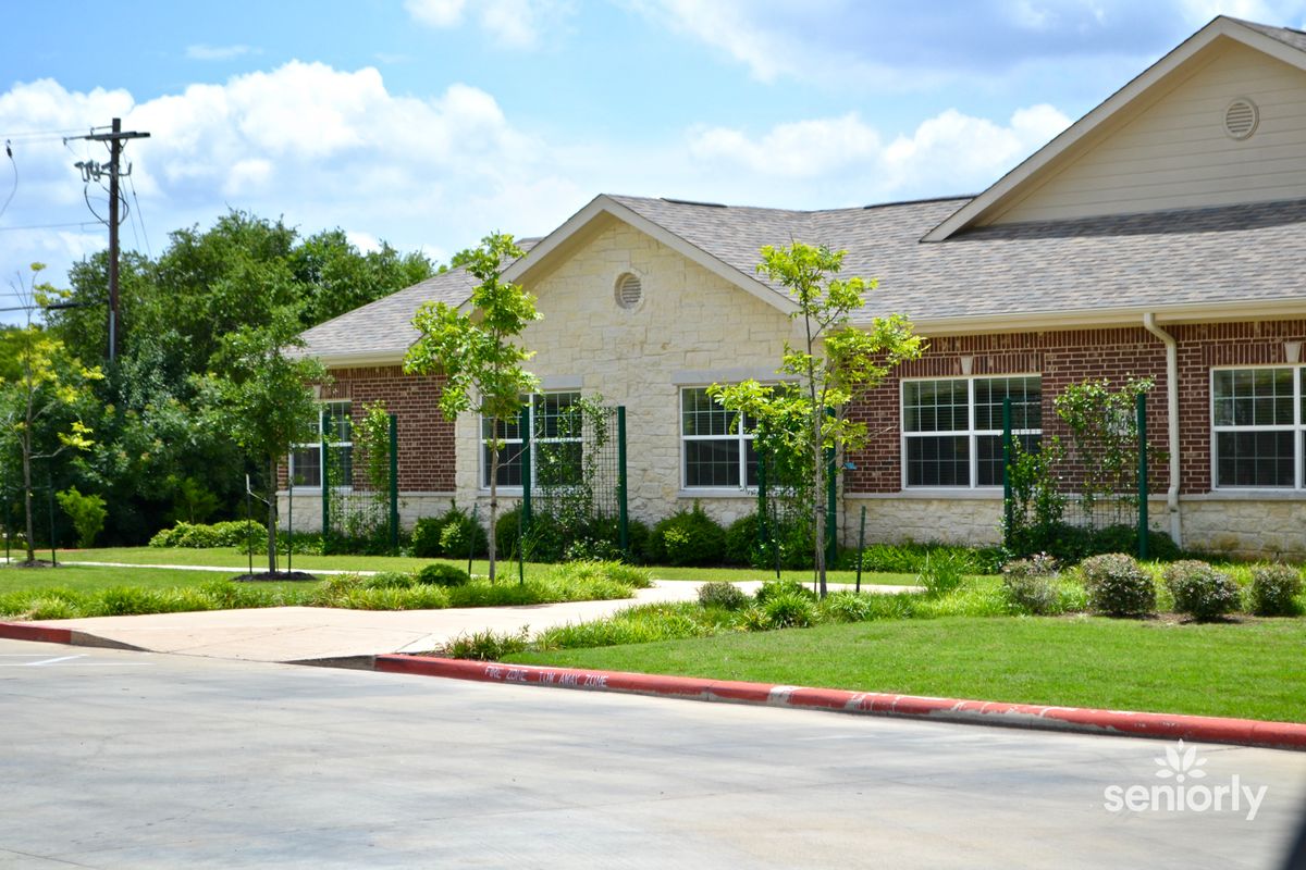 Senior living community, Pecan Ridge, featuring lush lawns, trees, and plants in a suburban city.