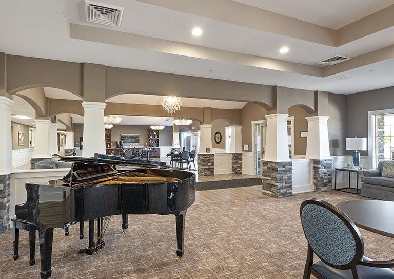 Senior playing grand piano in the art-filled lounge of Hampton Manor, a senior living community.