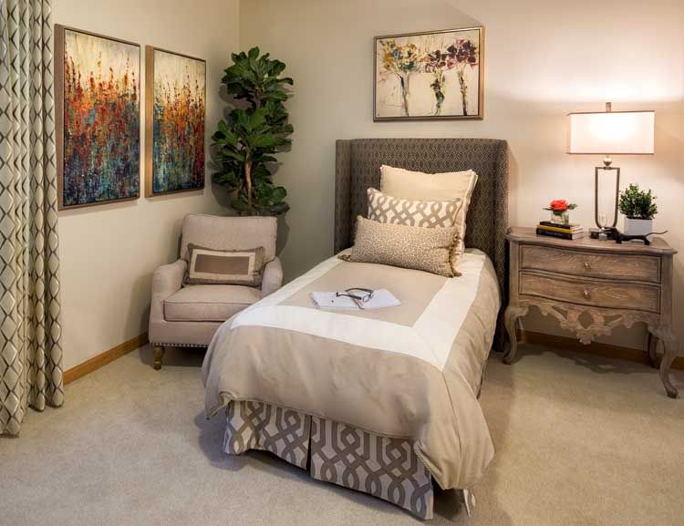 Senior living community bedroom at Aspired Living of Prospect Heights with art, decor and furniture.