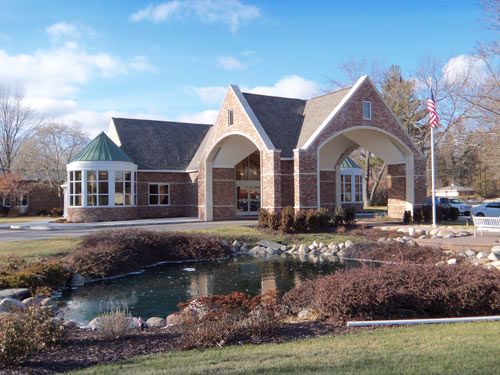 Manoogian Manor senior living community with waterfront villas, lush lawns, and gothic architecture.