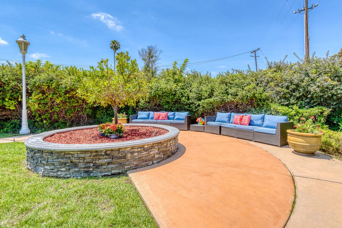 Senior residents enjoying the outdoor patio, garden, and hot tub at Pacifica Senior Living Newport Mesa.