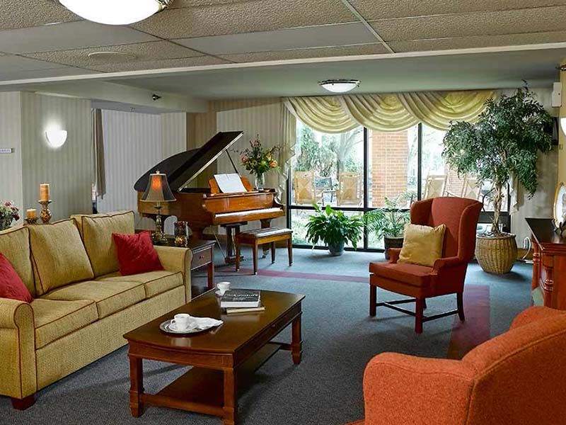 Senior living room at Celebration Villa of Highland Crossing with grand piano and cozy decor.