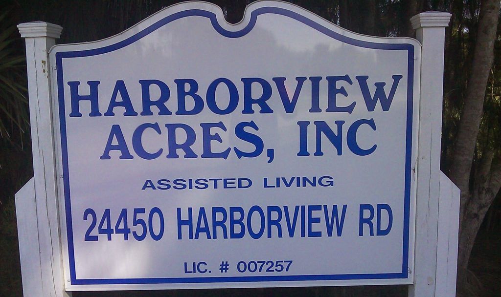 Signboard of Harborview Acres senior living community outdoors with road sign and text.