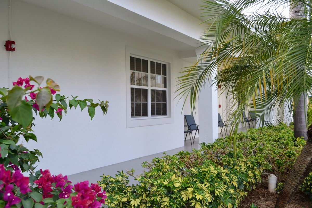 Senior living community villa at Banyan Place with lush garden, potted plants, and cozy interior design.