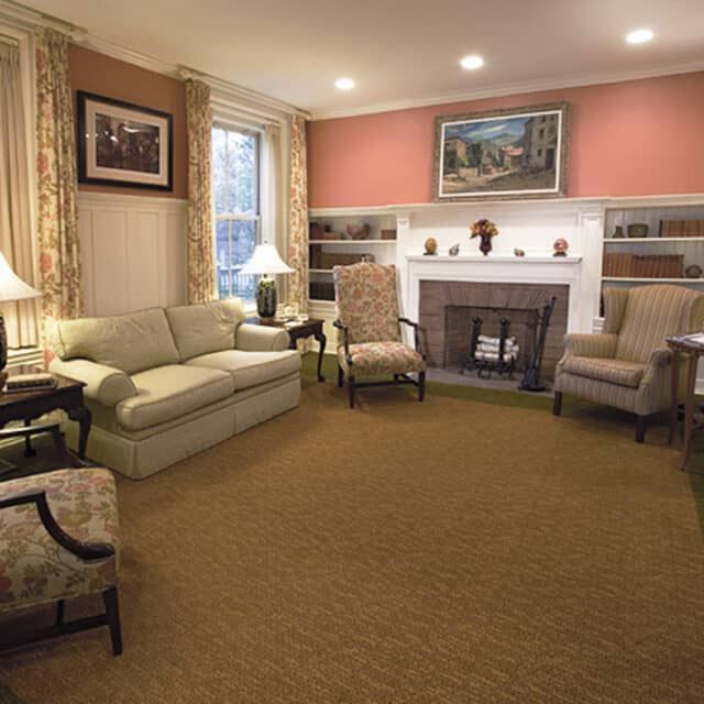 Senior enjoying a cozy living room with elegant furniture and art at The Cambridge Homes.