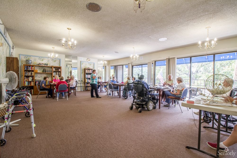 Senior residents enjoying a book in the library of Burbank Retirement Villa East.