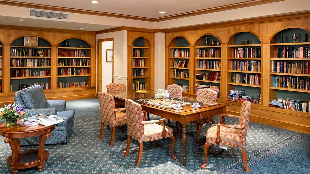 Senior living community Atria Marina Place featuring a library with books, furniture, and dining area.