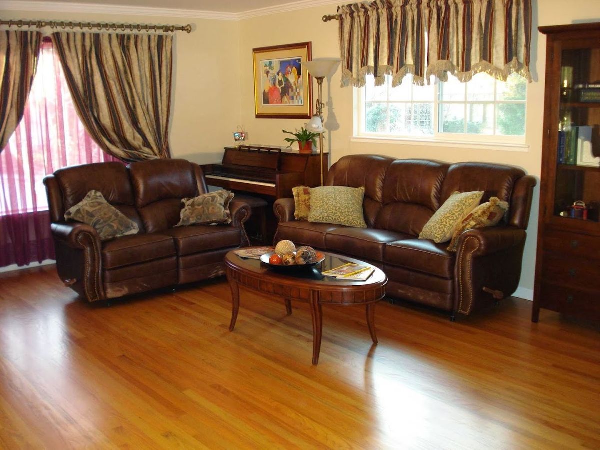 Seniors enjoying a cozy living room with hardwood floors, piano, and fresh fruit in Enchanted Garden community.