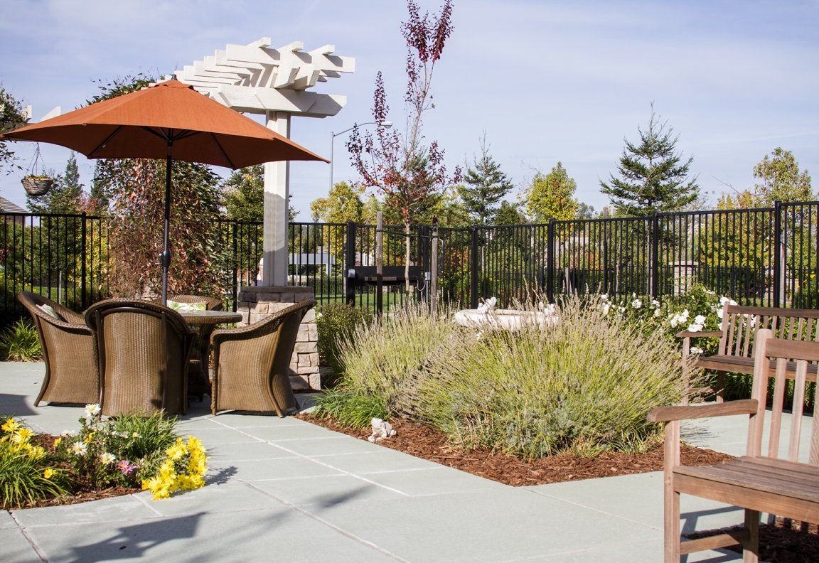 Senior living community Sunrise of Rocklin featuring lush gardens, park scenery, and cozy patio spaces.