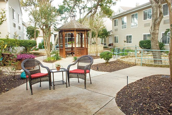 Senior living community, Juniper Village at Spicewood Summit, featuring outdoor patio and lush greenery.