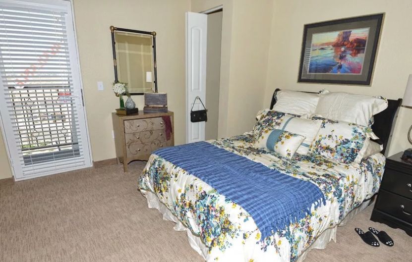 Interior view of a bedroom at Caliche Senior Living featuring modern decor, furniture, and electronics.